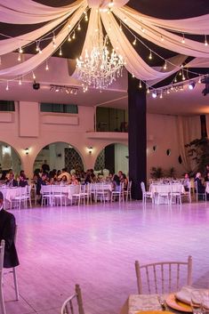 an empty ballroom with tables and white chairs