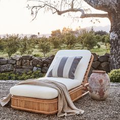 an outdoor chaise lounge with a blanket on it in front of a stone wall