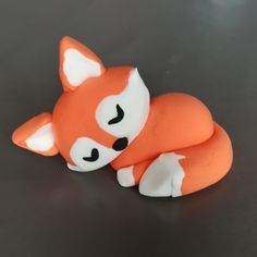 an orange and white toy laying on top of a black table with its eyes closed