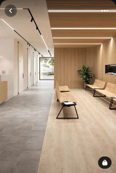 an empty waiting room with two benches and a flat screen tv mounted on the wall