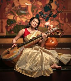 a woman sitting on top of a table holding a musical instrument