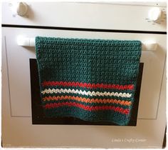 a green crocheted dishcloth hanging from the oven