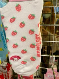 socks with strawberries on them are hanging in a rack at a store while someone is wearing a face mask