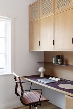 a desk with a chair, lamp and books on it in front of a window