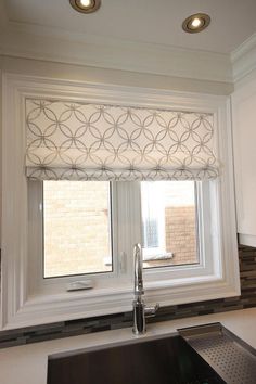 a kitchen window with roman shades in it