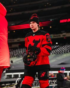 a hockey player in red and black uniform standing on the ice