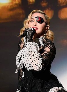 lady in black and white dress with polka dots on her face, holding a microphone