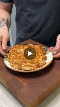 a man is holding a plate with food on it and he is about to cut the pizza