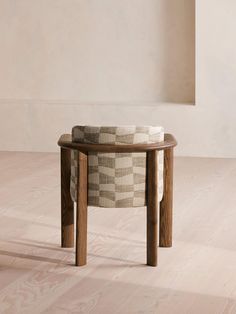 a round wooden table with a checkered upholstered seat on it's side