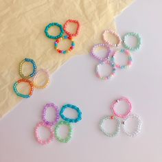 six small beaded bracelets sitting next to each other on a piece of paper