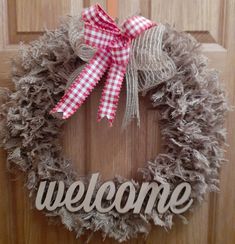 a welcome sign is hanging on a door with a burlock and red bow