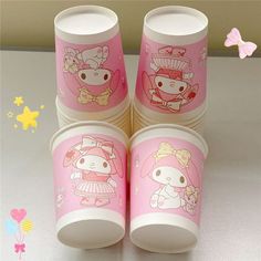 four hello kitty cups sitting on top of a table