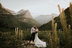 a bride and groom standing on a path in the mountains