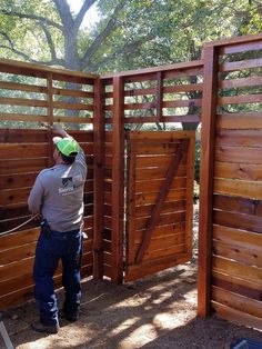 a man standing in front of a wooden fence with a green ball on his head