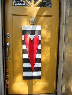 a yellow door with a red heart painted on the front and side panels, next to a black and white striped door