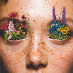 a woman with freckles on her face has flowers in their eyes