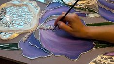 a person is painting flowers on a piece of glass with a brush and watercolor