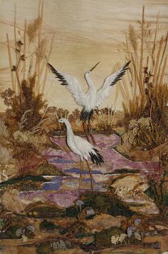 two white birds flying over a body of water next to tall grass and reeds