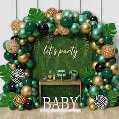 a baby shower backdrop with balloons and greenery on the wall, it's party