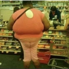 a woman in pink is standing in front of a store counter with her back to the camera