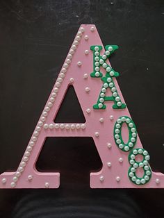 a pink and green plastic letter with pearls on the letters'a - z '