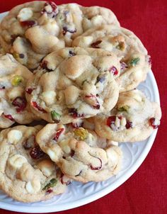 a white plate topped with cookies covered in cranberry toppings on top of a red table