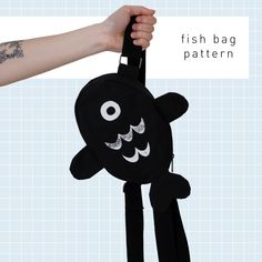 a hand holding a black bag with a fish design on the front and back straps