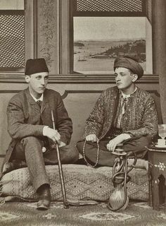 an old photo of two men sitting next to each other