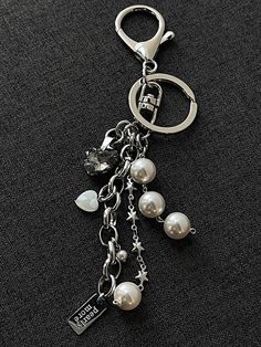 a keychain with pearls and charms hanging from it's side on a black surface