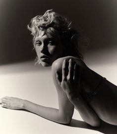 a black and white photo of a woman laying on the floor with her hands behind her head