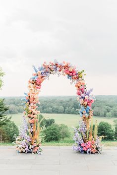 an outdoor ceremony setup with flowers on the arch and greenery in the back ground