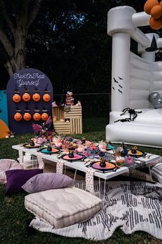 an outdoor halloween party with decorations and food on the grass in front of a large inflatable bouncer