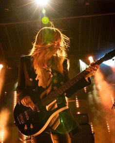 a woman playing a guitar on stage at a concert