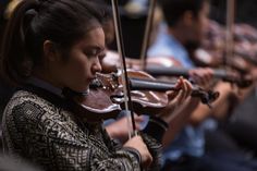 a woman playing the violin while others watch