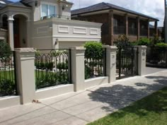 a house with an iron fence in front of it and bushes on the other side