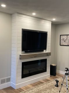 a living room with a large flat screen tv mounted on the wall next to a fire place