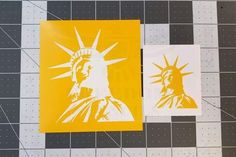 two yellow and white stickers depicting the statue of liberty on a tiled floor with black dots