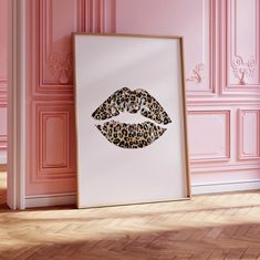 a leopard print on a pink wall next to a white frame with the image of a woman's lips