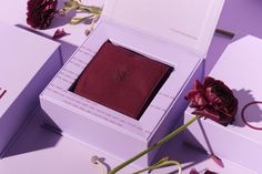 an open box with a red cloth inside and flowers in the corner next to it