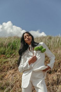 a woman in a white suit and broccoli is posing for the camera with her hands on her hips