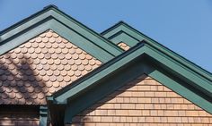 the roof of a house with green shingles and brown wood sidings on it