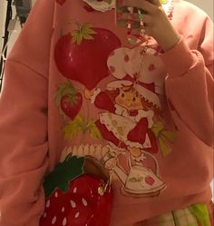 a woman wearing a strawberry sweater and holding a cell phone