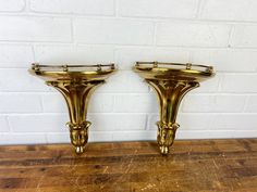 pair of brass candlesticks on wooden table with brick wall in backgroud