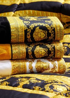 a stack of black and gold cloths sitting on top of a bed next to each other