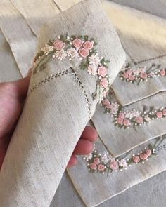 a hand is holding some fabric with flowers on it and stitching the edges together