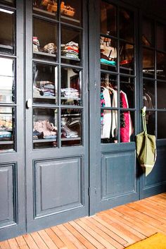 the inside of a clothing store with wooden flooring and large glass doors that open