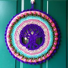 a crocheted doily hanging on a green door with pink and blue trim