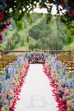 an outdoor ceremony setup with flowers and wooden benches in the foreground, overlooking a green hillside