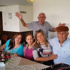 a group of people sitting at a table with their hands in the air and smiling