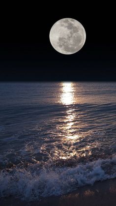 the moon is shining brightly over the water at night on the ocean shore with waves coming in